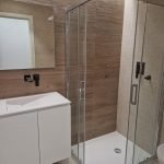 Moderne badkamer met glazen douchehoek en houten accenten