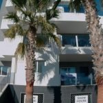 Moderne witte appartementengebouw met palmbomen en showhuisbordje