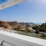 Uitzicht vanaf balkon met witte balustrade op heuvellandschap en blauwe zee