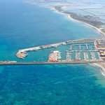 Luchtfoto van zeehaven met boten jachthaven en zoutpannen op achtergrond